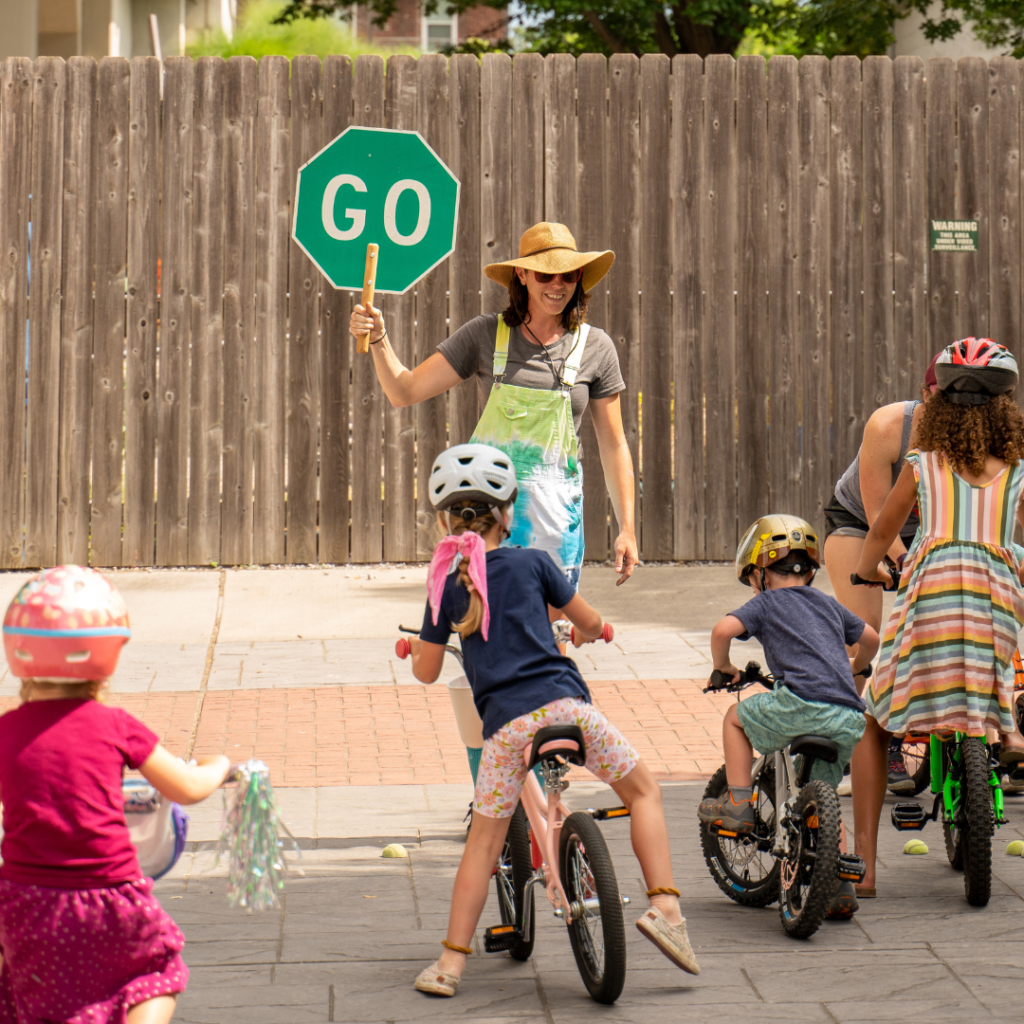 Instructor holding up a GO sign for kids who are learning to ride.
