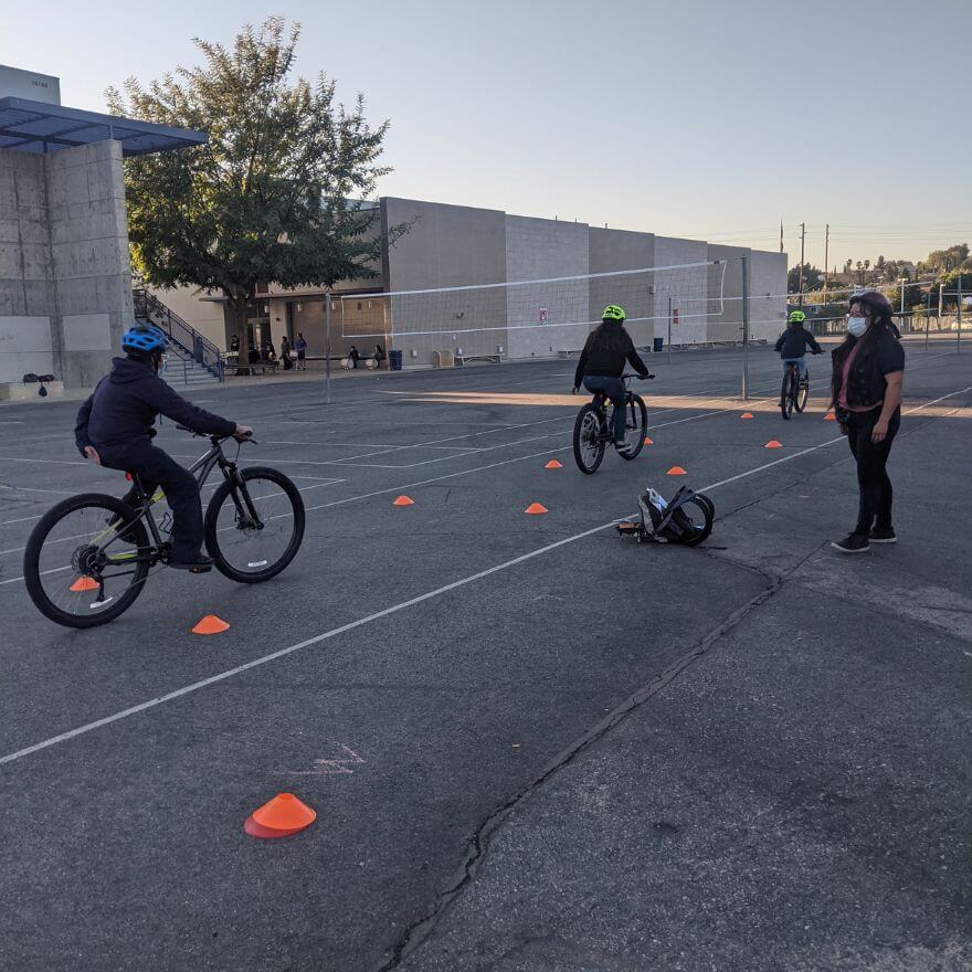 LCI Brenda Yancor instructing three students as they bike through cones in a parking lot